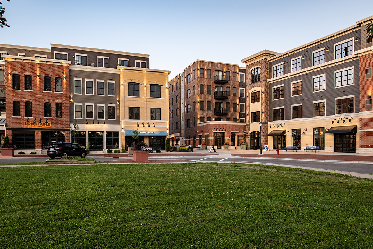 Street-level exterior of Middleton Center Phase II with retail storefronts, green lawn, and residential units above in downtown Middleton Wisconsin