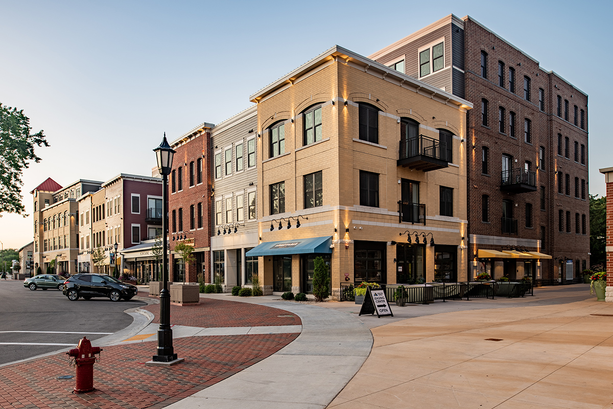 Corner street view of Middleton Center Phase II mixed-use building with brick and tan facade, clock tower, and street-level retail in downtown Middleton Wisconsin