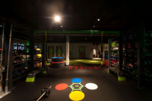 Fitness floor at Carbon World Health with exercise equipment, colored agility markers, and retail merchandise wall