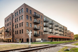 Panoramic exterior view of Middleton Center brick mixed-use building with railroad tracks and signal in the foreground