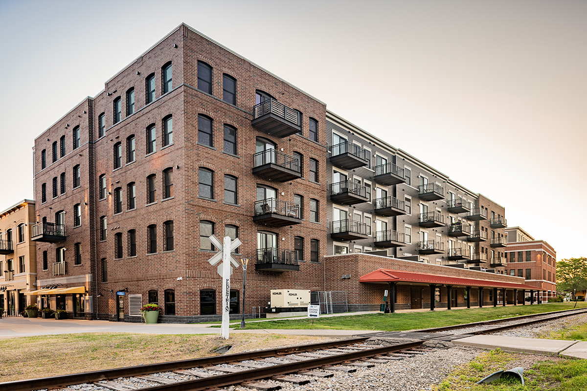 Panoramic exterior view of Middleton Center brick mixed-use building with railroad tracks and signal in the foreground