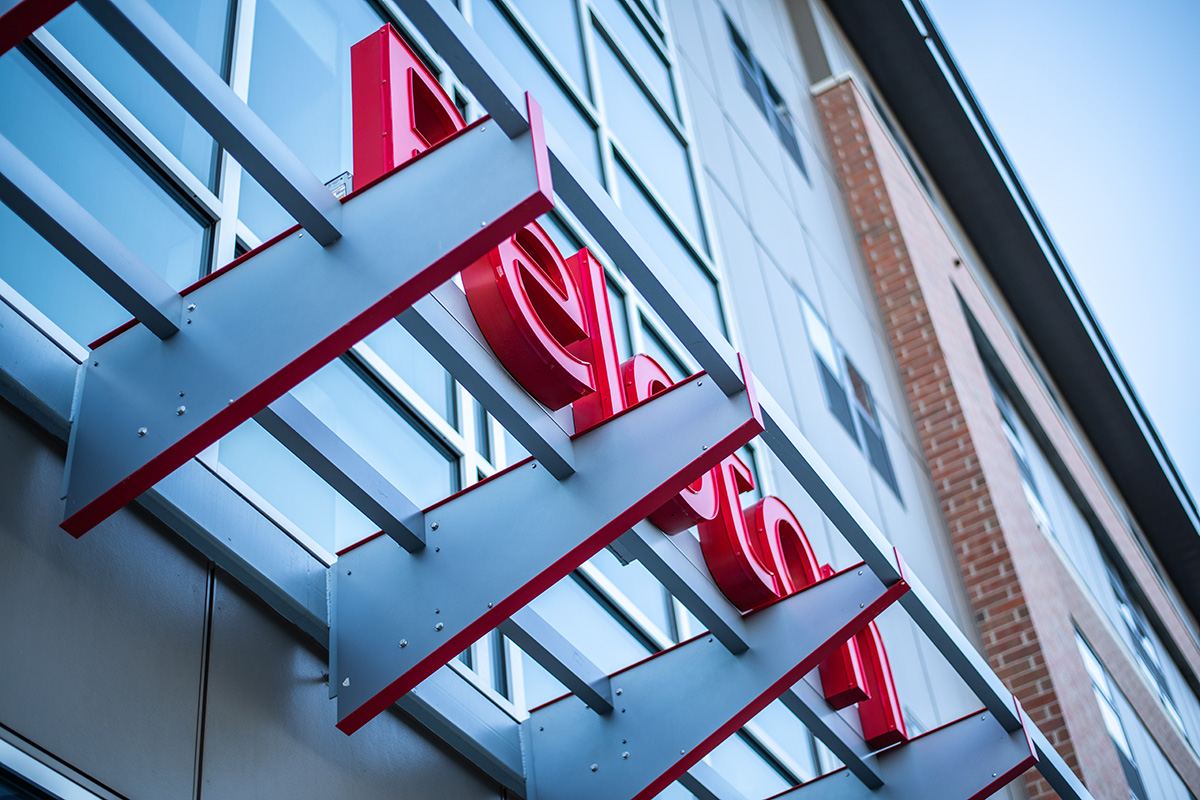 Close-up of red Peloton Residences building signage mounted on glass curtain wall facade