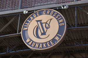 Close-up of Village Crossing Waunakee Wisconsin medallion signage mounted on steel truss structure